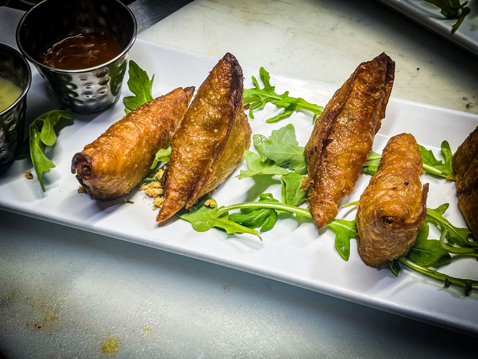 Crispy samosas with chicken, lamb, or vegetarian options, served with yogurt cucumber dip at Simone on Sunset.