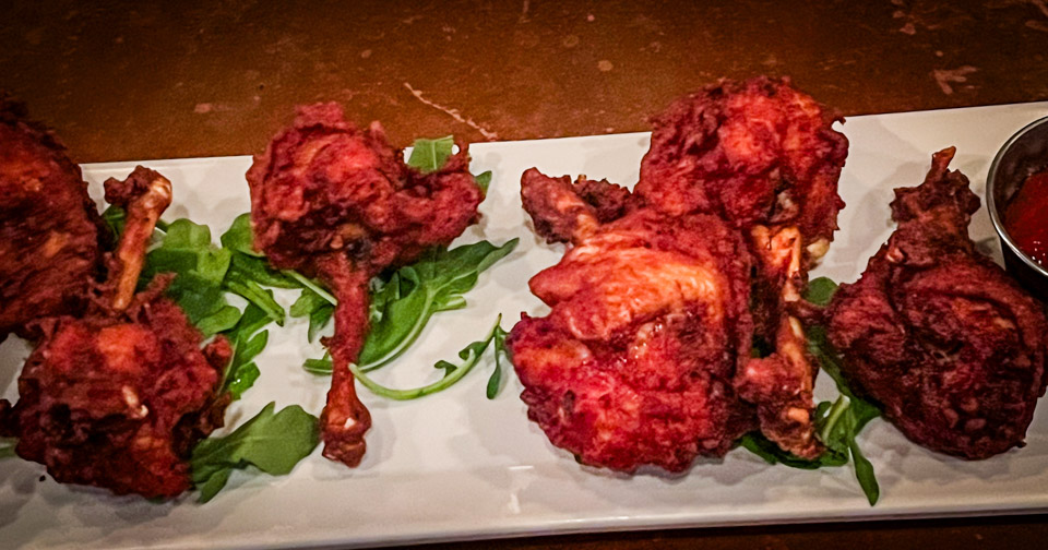 Chicken lollipops with housemade chili sauce on a plate at Simone on Sunset.