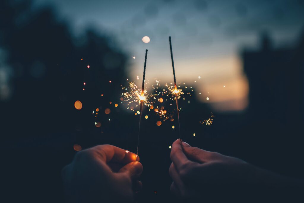 People celebrating with sparklers during a festive outdoor moment at sunset.